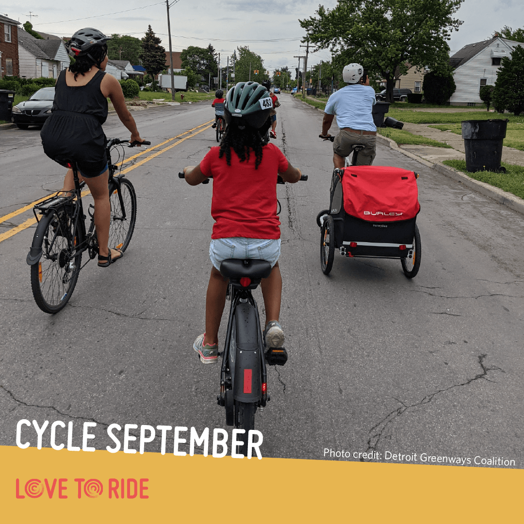 A family riding on a residential road, shown from behind. One person carries a trailer on their bike. The text says ‘Cycle September. Photo credit: Detroit Greenways Coalition’ and the Love to Ride logo is displayed. A family riding on a residential road, shown from behind. One person carries a trailer on their bike. The text says ‘Cycle September. Photo credit: Detroit Greenways Coalition’ and the Love to Ride logo is displayed.
