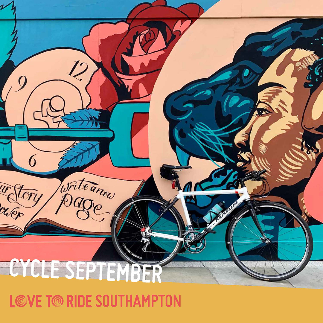 A bike propped up against a wall covered in a large colourful mural which contains images of faces, a key, and an open book containing the words ‘your story your power, write a new page’. A bike propped up against a wall covered in a large colourful mural which contains images of faces, a key, and an open book containing the words ‘your story your power, write a new page’.