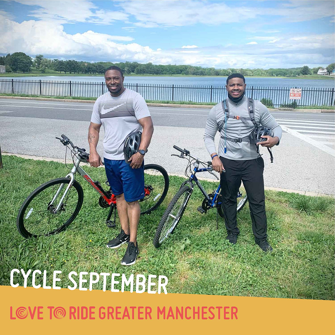 Two men stand with bikes on a grass verge next to a road and in front of a lake. They both hold helmets and are smiling. The text says ‘Cycle September’ and the Love to Ride logo is displayed. Two men stand with bikes on a grass verge next to a road and in front of a lake. They both hold helmets and are smiling. The text says ‘Cycle September’ and the Love to Ride logo is displayed.