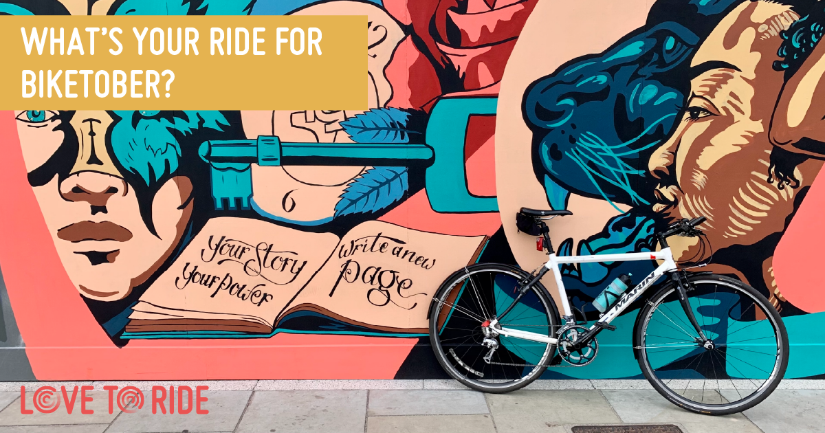 A bike propped up against a wall covered in a large colourful mural which contains images of faces, a key, and an open book containing the words ‘your story your power, write a new page’. The text on the asset says ‘what’s your ride for Biketober?’. A bike propped up against a wall covered in a large colourful mural which contains images of faces, a key, and an open book containing the words ‘your story your power, write a new page’. The text on the asset says ‘what’s your ride for Biketober?’.