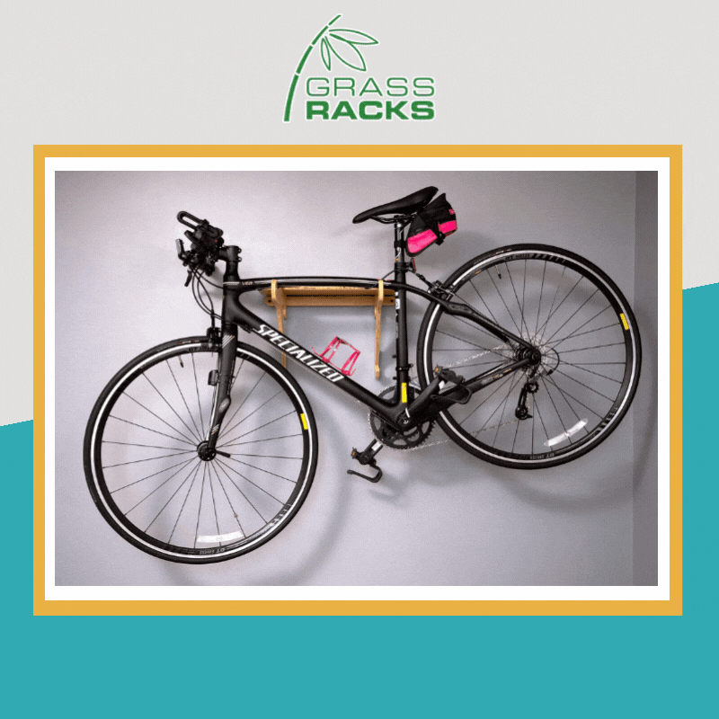 A square asset with a blue and grey background. The GrassRacks logo is at the top. An image of a black bike on a GrassRack hanging on the wall in the centre with a yellow frame around it. A square asset with a blue and grey background. The GrassRacks logo is at the top. An image of a black bike on a GrassRack hanging on the wall in the centre with a yellow frame around it.