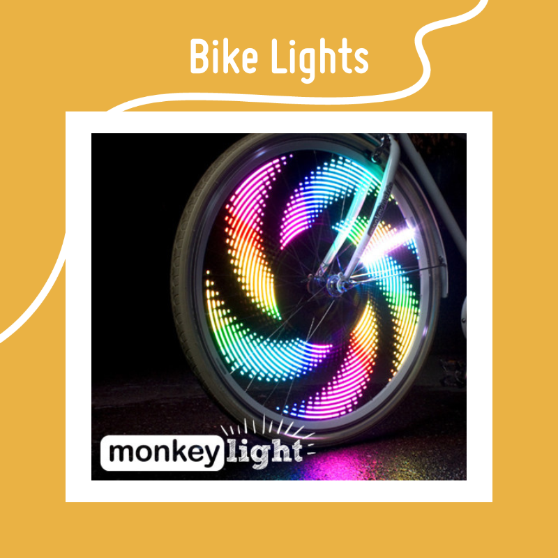 A rainbow bike light spinning in a wheel on a black background and the Monkey Light logo. It's surrounded by a yellow background and the text Bike Lights A rainbow bike light spinning in a wheel on a black background and the Monkey Light logo. It's surrounded by a yellow background and the text Bike Lights